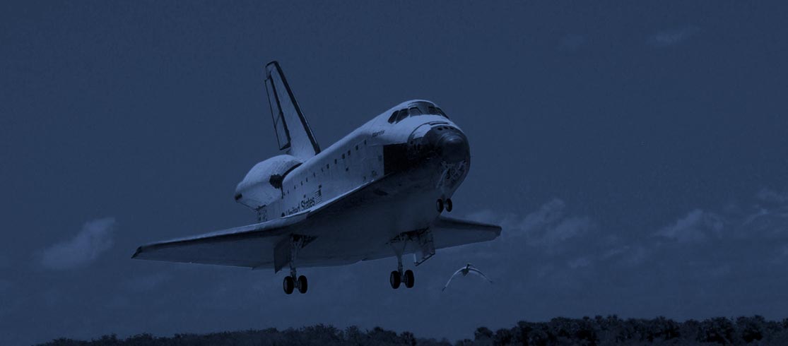 Space shuttle landing on a runway at night