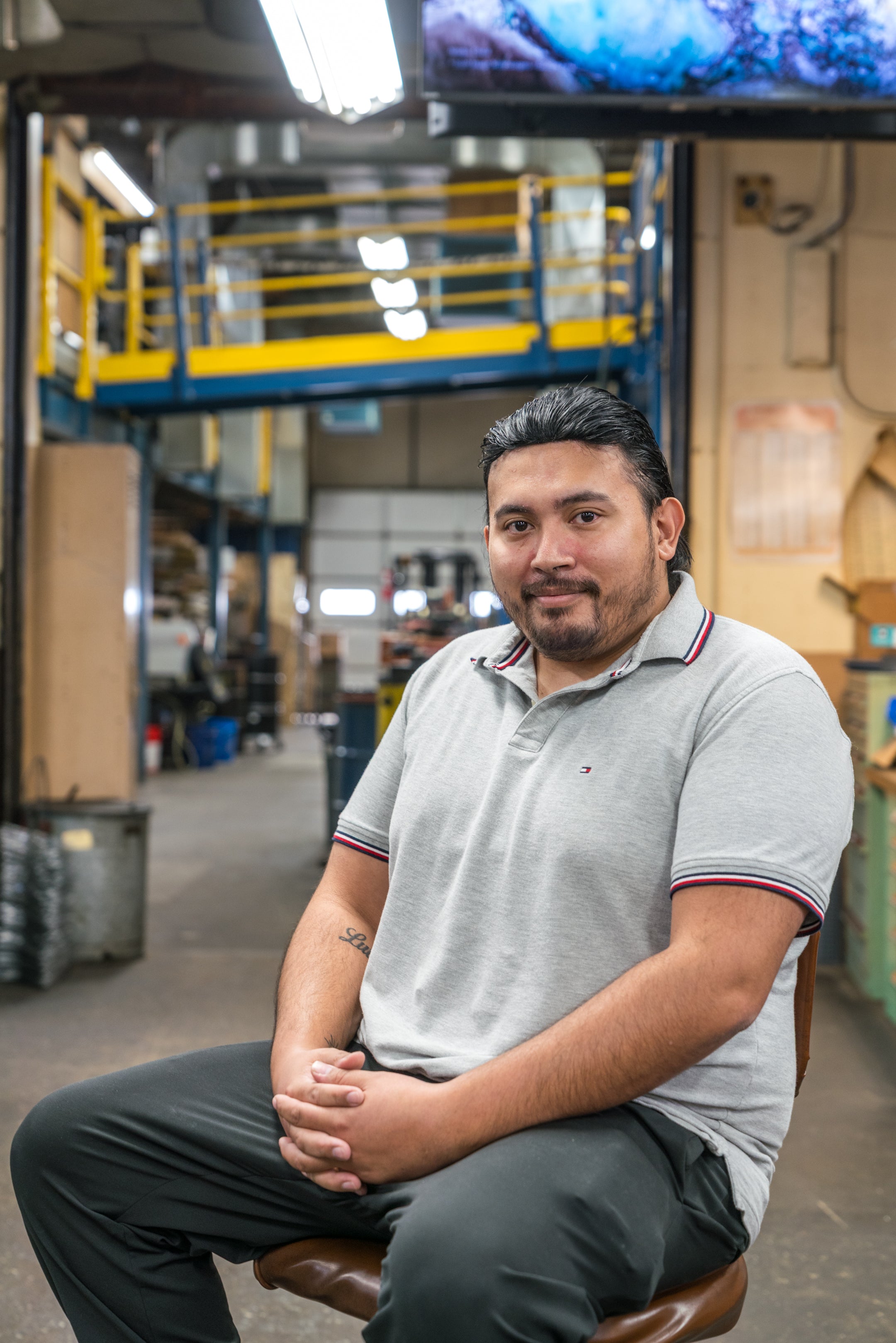 Man sitting in a warehouse setting with industrial equipment in the background