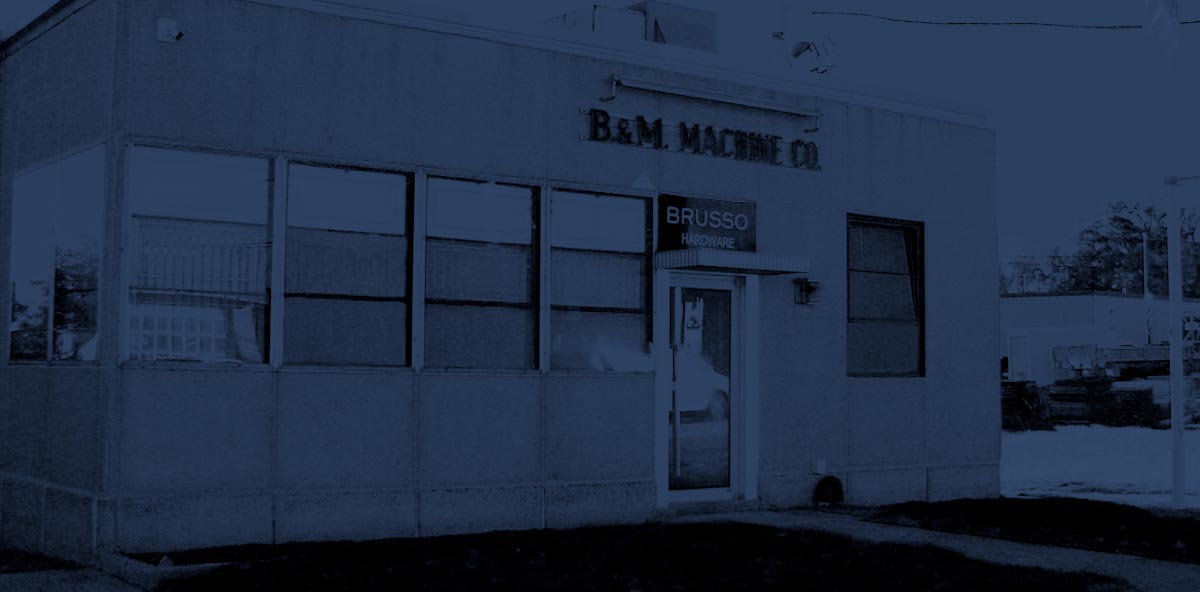 White building with 'B&M Machine Co' sign on a dark background